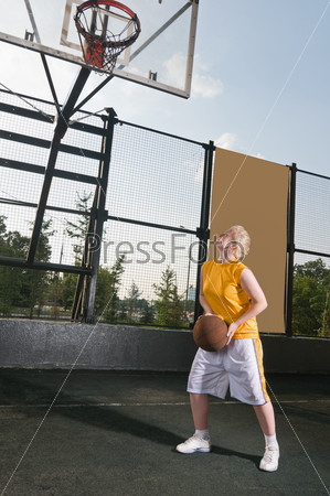 Teenage girl with basketball at the street playground