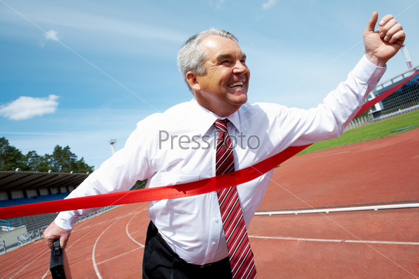 Photo of happy mature businessman crossing finish line during race