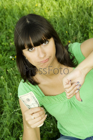Young woman outdoors holding a cash. Thinks. Little money