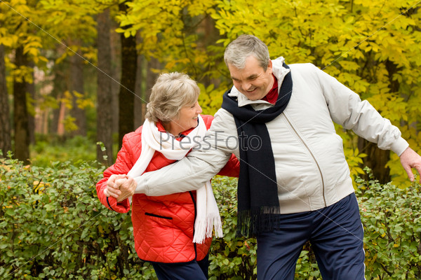Photo of two aged people having fun during walk in autumn forest, stock photo