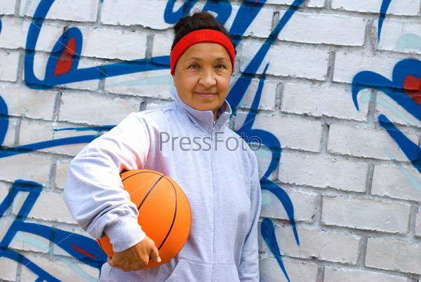 Senior woman with a basketball, graffiti background