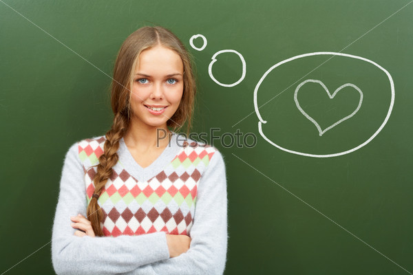 Portrait of pretty girl by the blackboard thinking of falling in love