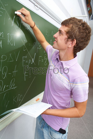 Portrait of smart lad by the blackboard writing formulae