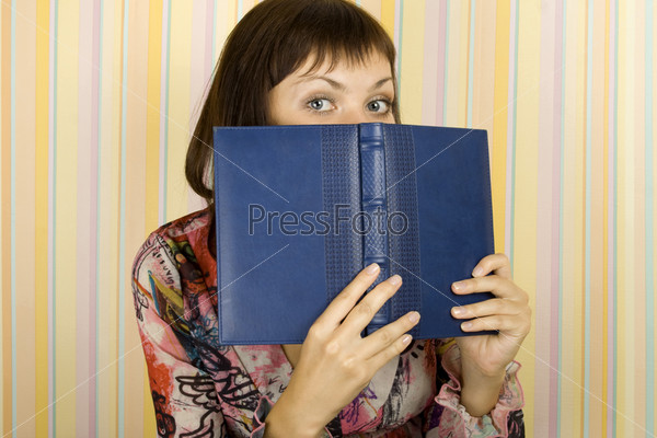 Young beautiful girl in the room face covered notebooks