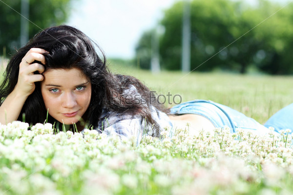 Portrait of young woman lying on a green lawn, stock photo