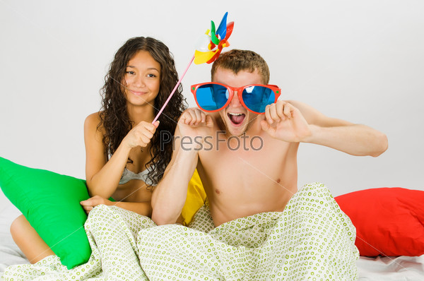 Young couple have some fun at the bedroom with colorful pillows