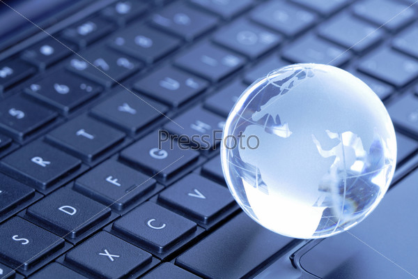 Glass globe lying on black laptop computer keyboard