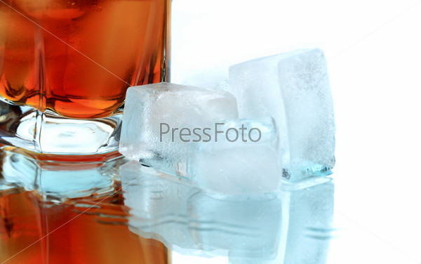 Glass of whiskey with ice cubes on white background with reverberation, stock photo