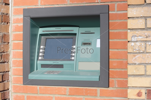 a cash dispenser against the background wall of brick