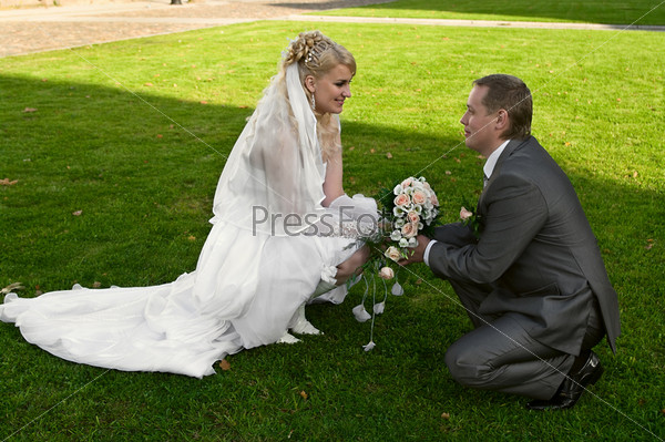 Loving newly-married couple on green grass