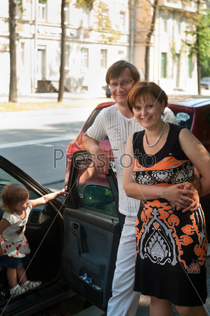 Happy parents near a new car and child here
