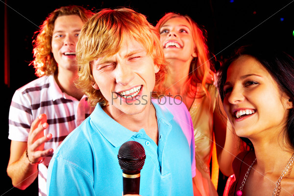 Photo of funny guy singing at party with happy girlfriend near by