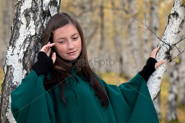 A sad woman in the background of the autumn forest.