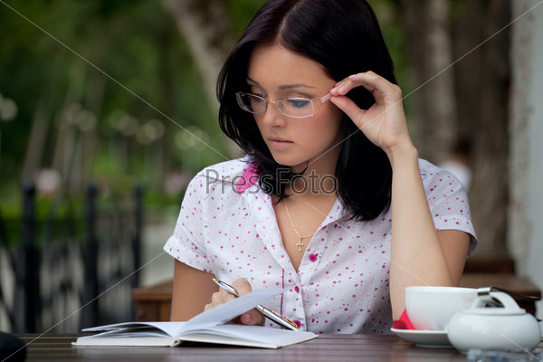 Молодая красивая девушка-студентка с блокнотом в кафе