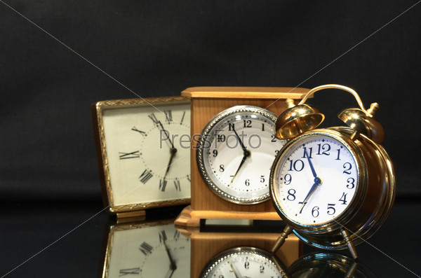 Three various alarm clocks isolated on dark background, stock photo