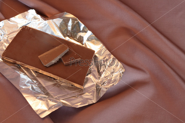 Chocolate bar in open cover isolated on nice background with brown cloth