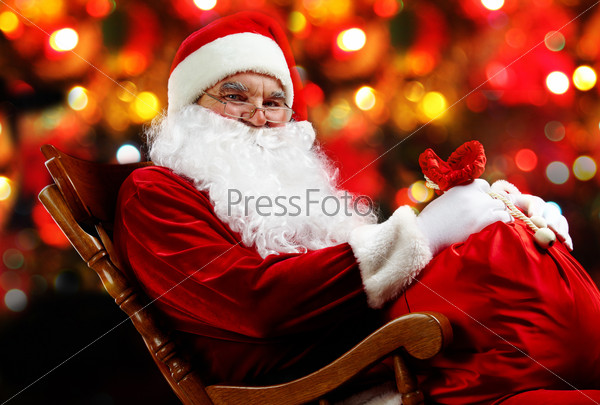 Santa sitting with a sack against sparkling lights