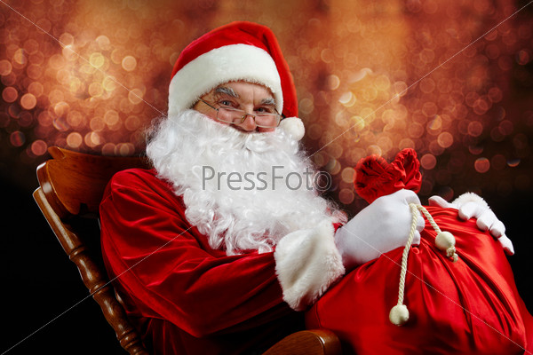 Santa sitting with a sack against glaring lights