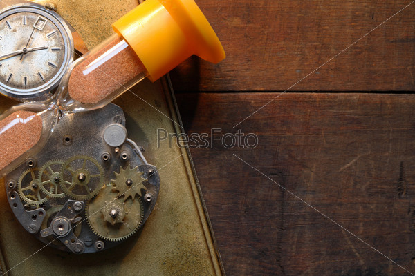 Hourglass, old watch and clock mechanism lying on wooden background with copy space, stock photo
