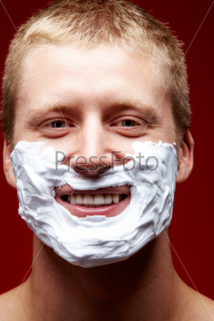Portrait of handsome man with foam on face on a red background