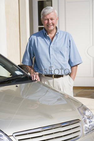 Senior man standing next to new car outside house