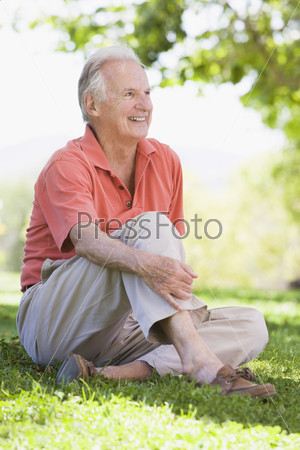 Senior man relaxing in countryside sitting on grass