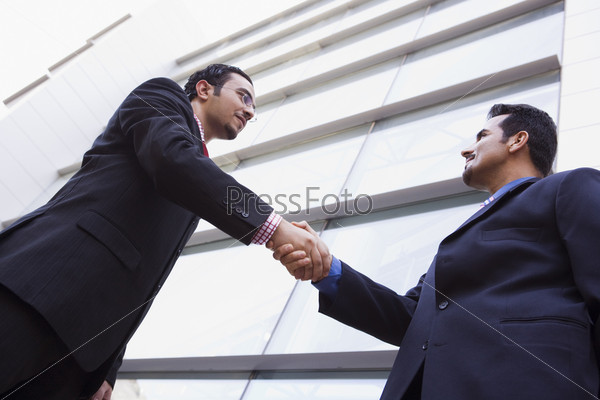 Two businessmen meeting outside modern office building