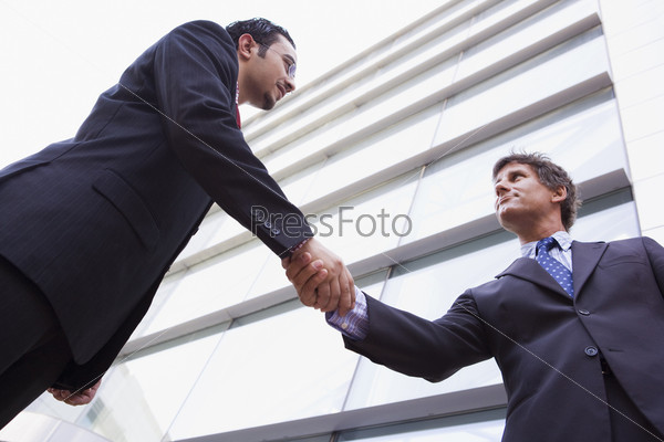 Businessman shaking hands outside modern office building