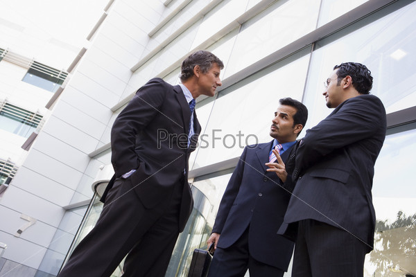 Group of businessmen talking outside modern office
