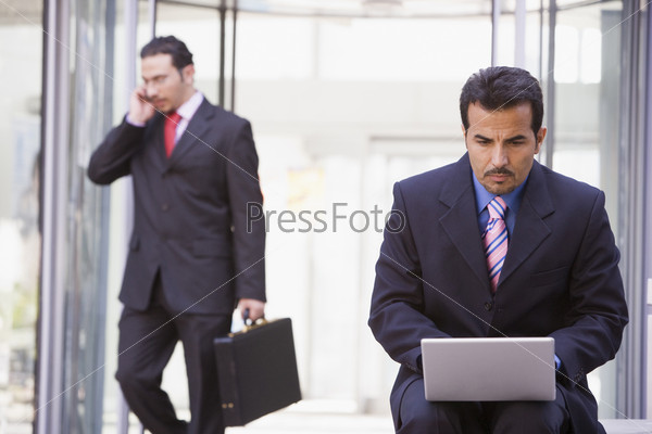 Businessman working at laptop outside office