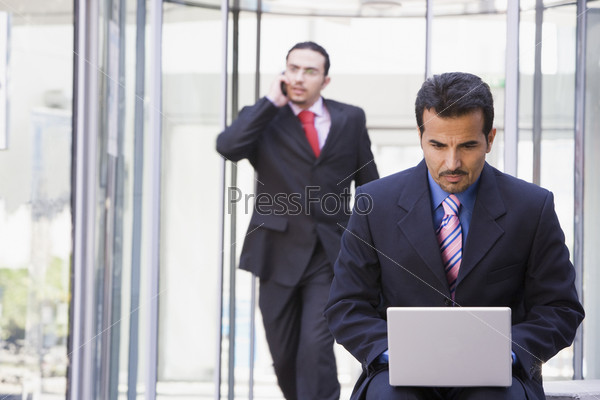Businessman working at laptop outside office