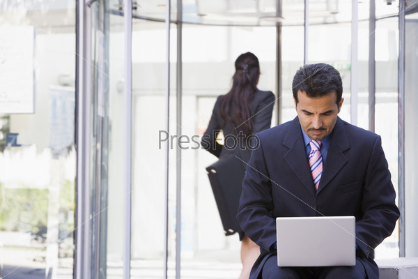 Businessman using laptop computer outside office