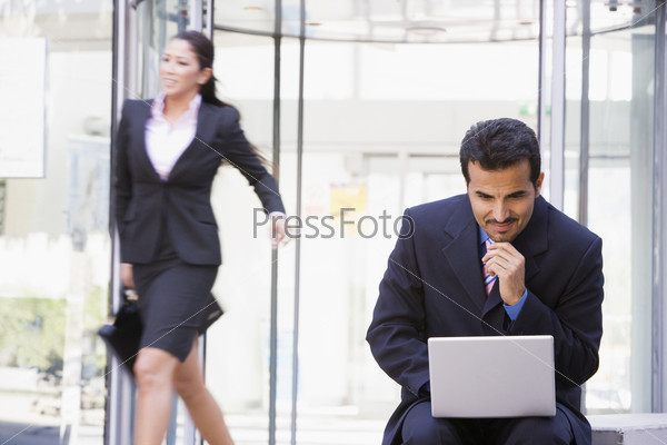 Businessman working outside at laptop outside office