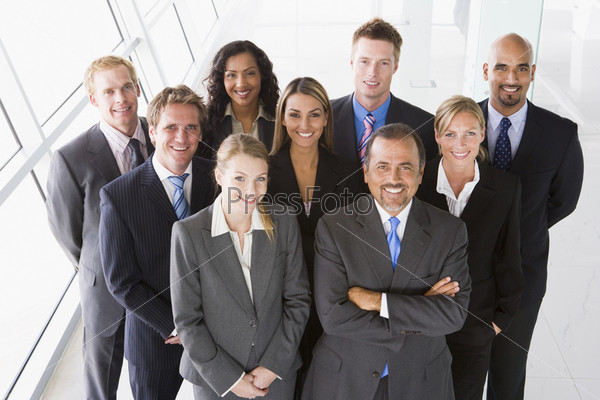 Group of co-workers standing in office space smiling (
