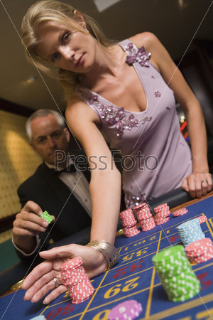 Couple placing bet at roulette table in casino