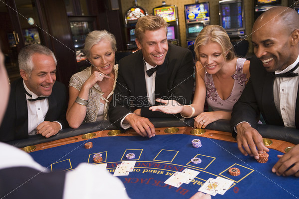 Five people sitting around blackjack table in casino