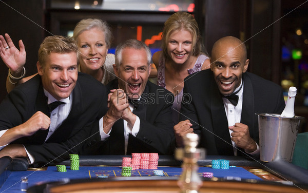 Group of friends celebrating win at roulette table in casino