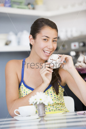 A young woman eating cake in a cafe
