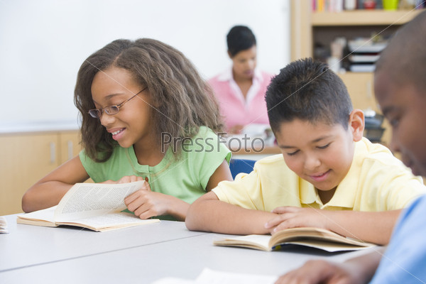Group of pupils reading books whilst seated at desk