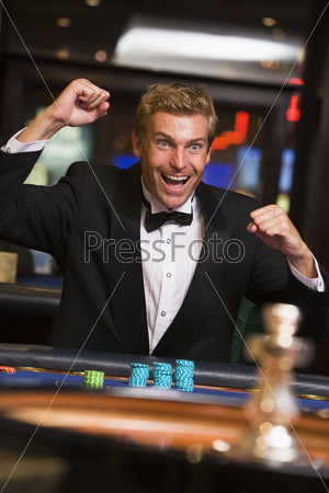 Man in casino winning at roulette and smiling (selective focus)