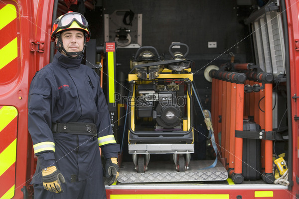Firefighter standing by the equipment in a small fire engine