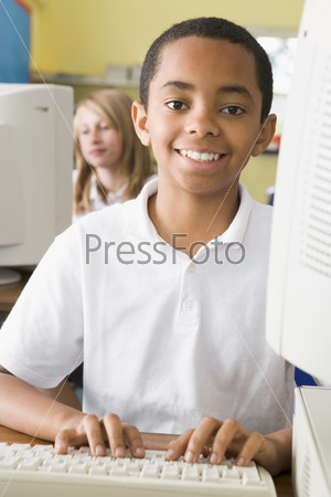 Student at computer terminal typing with student in background (selective focus)