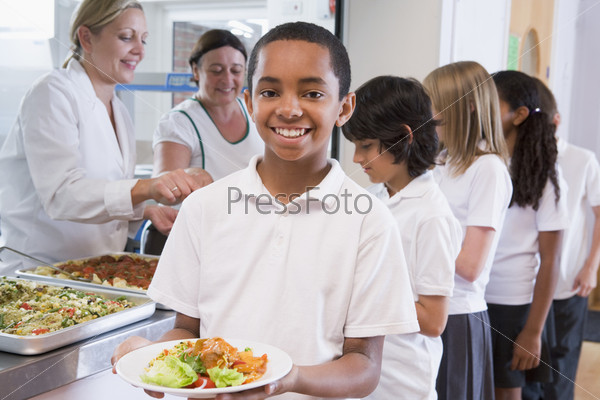 Students in cafeteria line with one holding his healthy meal and looking at camera
