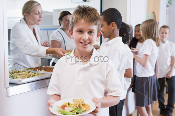 Students in cafeteria line with one holding his healthy meal and looking at camera