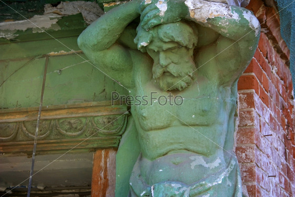 Statue - the male figure holds a wall of an old building
