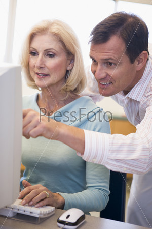 Man and woman at computer typing and pointing (high\
key)
