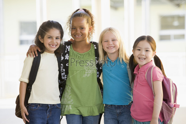Four students outside school standing together smiling (high key)