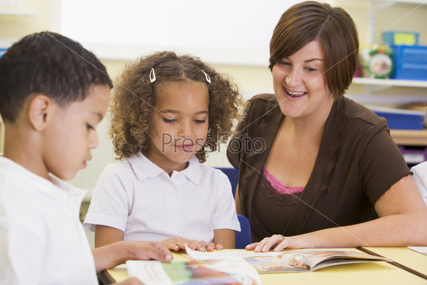 Schoolchildren and their teacher reading in class