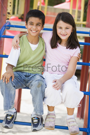 Two children in playground sitting on climbing frame