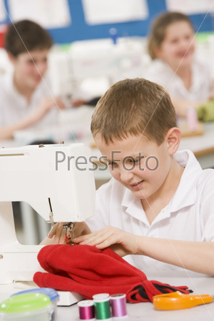 Schoolboy using a sewing machine in sewing class